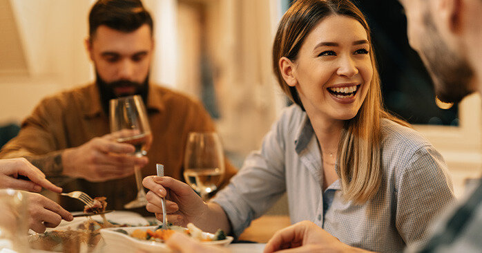 Friends at dinner, drinking wine and laughing.